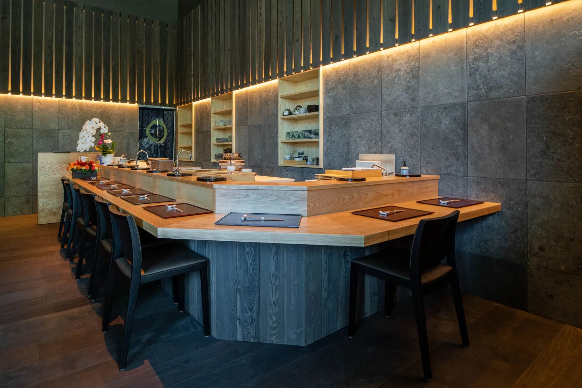 เคาน์เตอร์ไม้ยาวก่อนเปิดร้าน ที่รองจานเรียงเป็นแถว ไฟเส้นอุ่นส่องลงจากผนังหิน